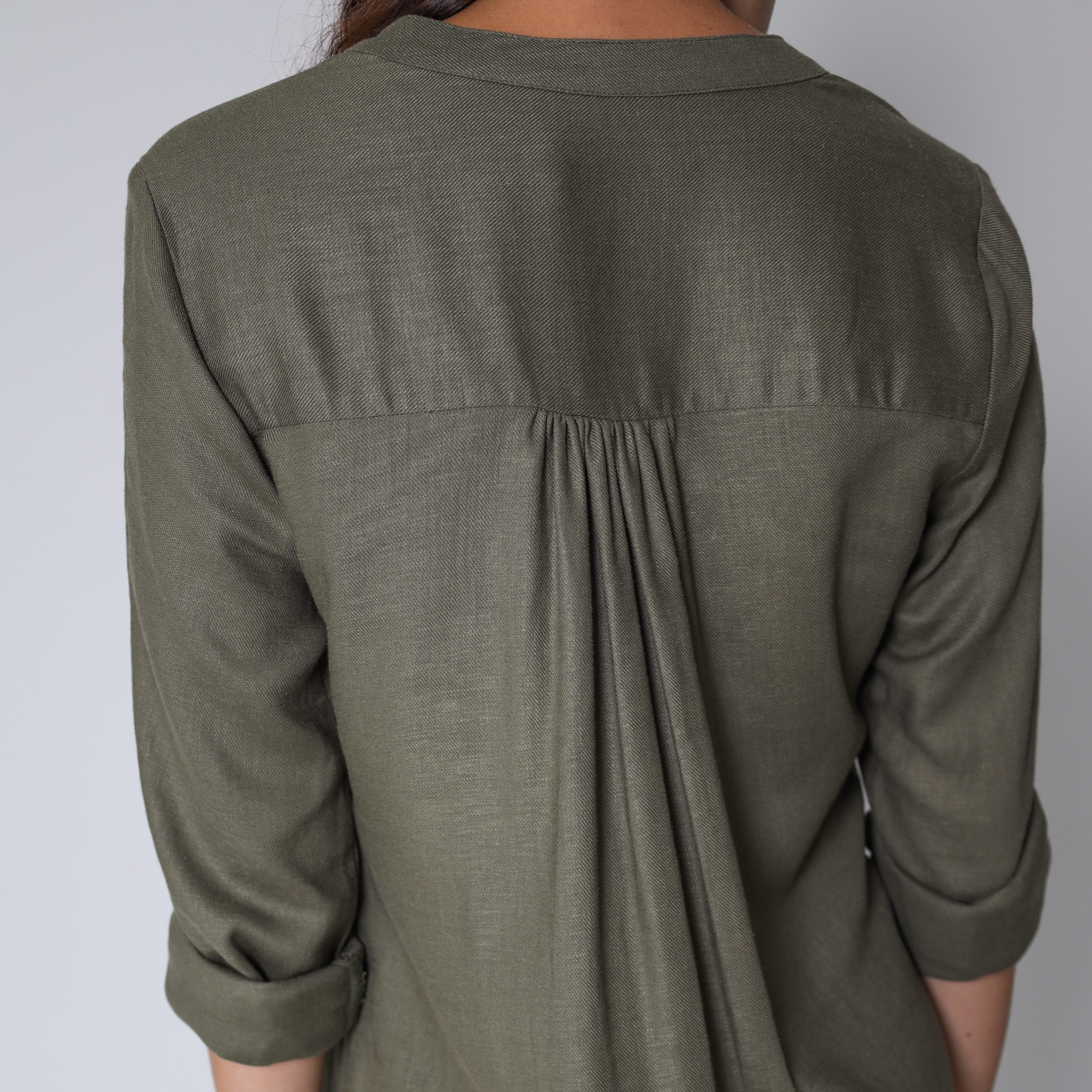 Shea green dress by Trinity hanging on a wooden hanger, showcasing a stylish consignment women's fashion piece.