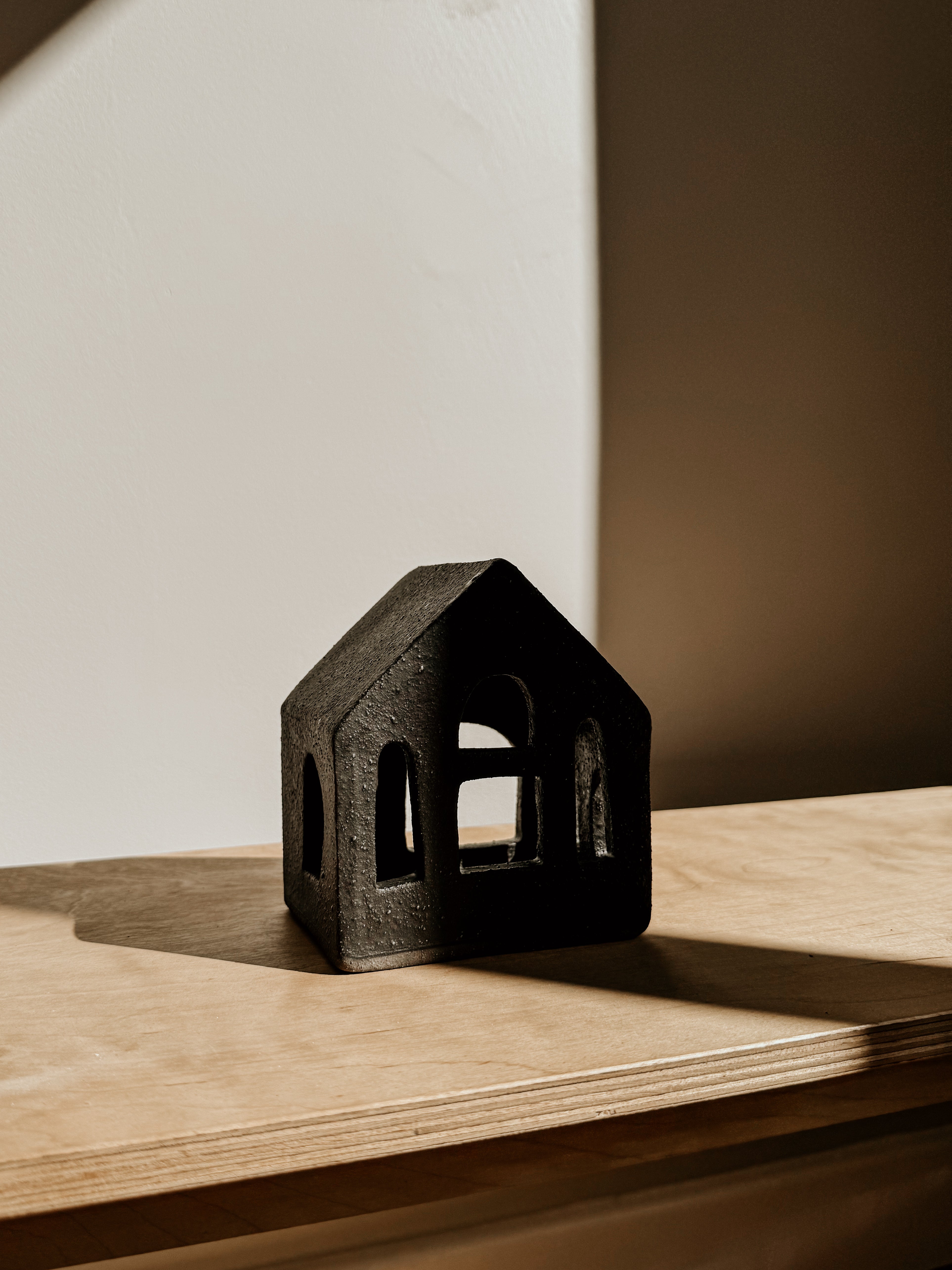 Small black tea light house candle holder by Delphine, crafted for cozy ambiance, shown in natural light.