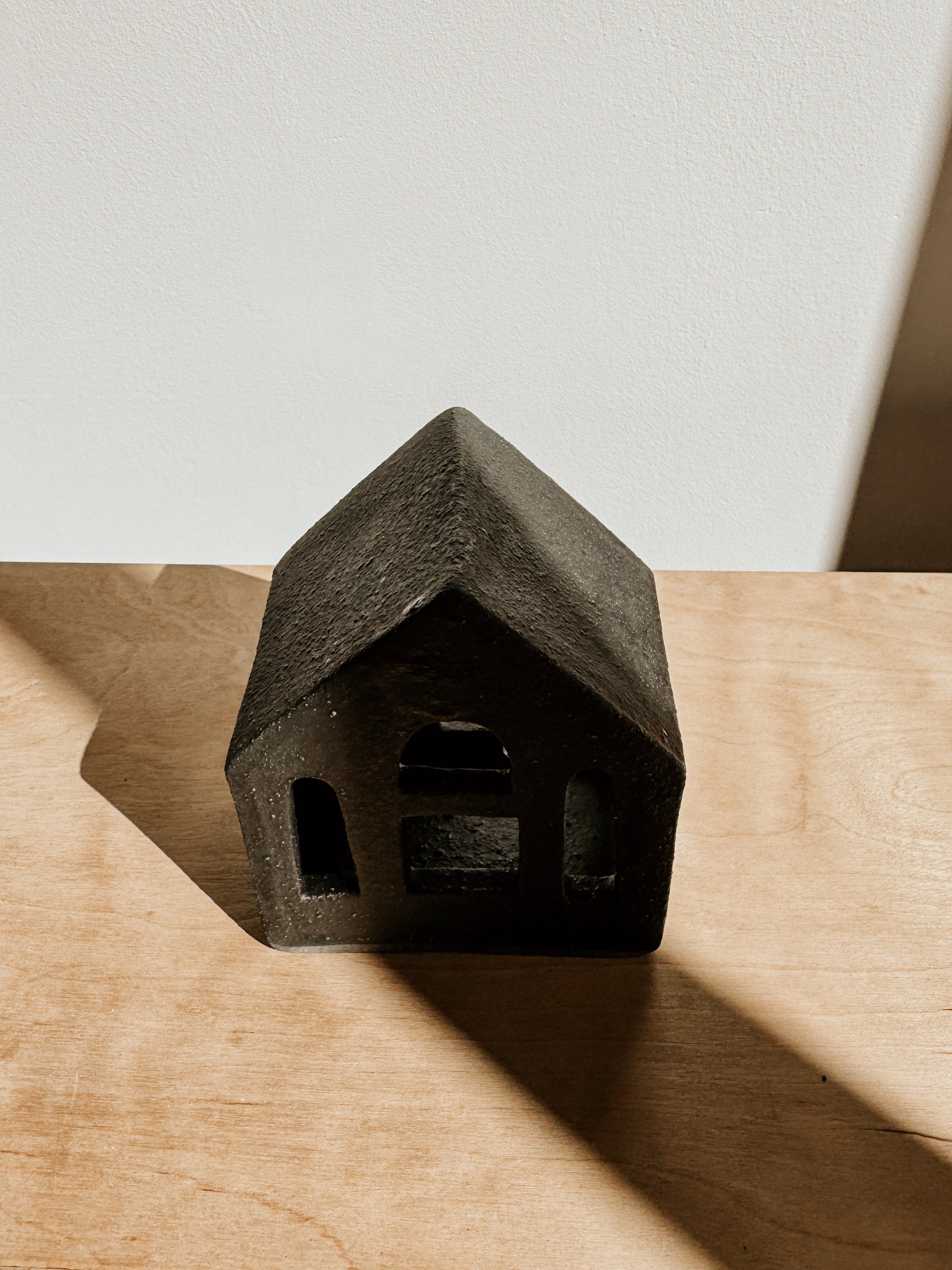 Small black tea light house candle holder by Delphine, with a cozy house design and open window details.