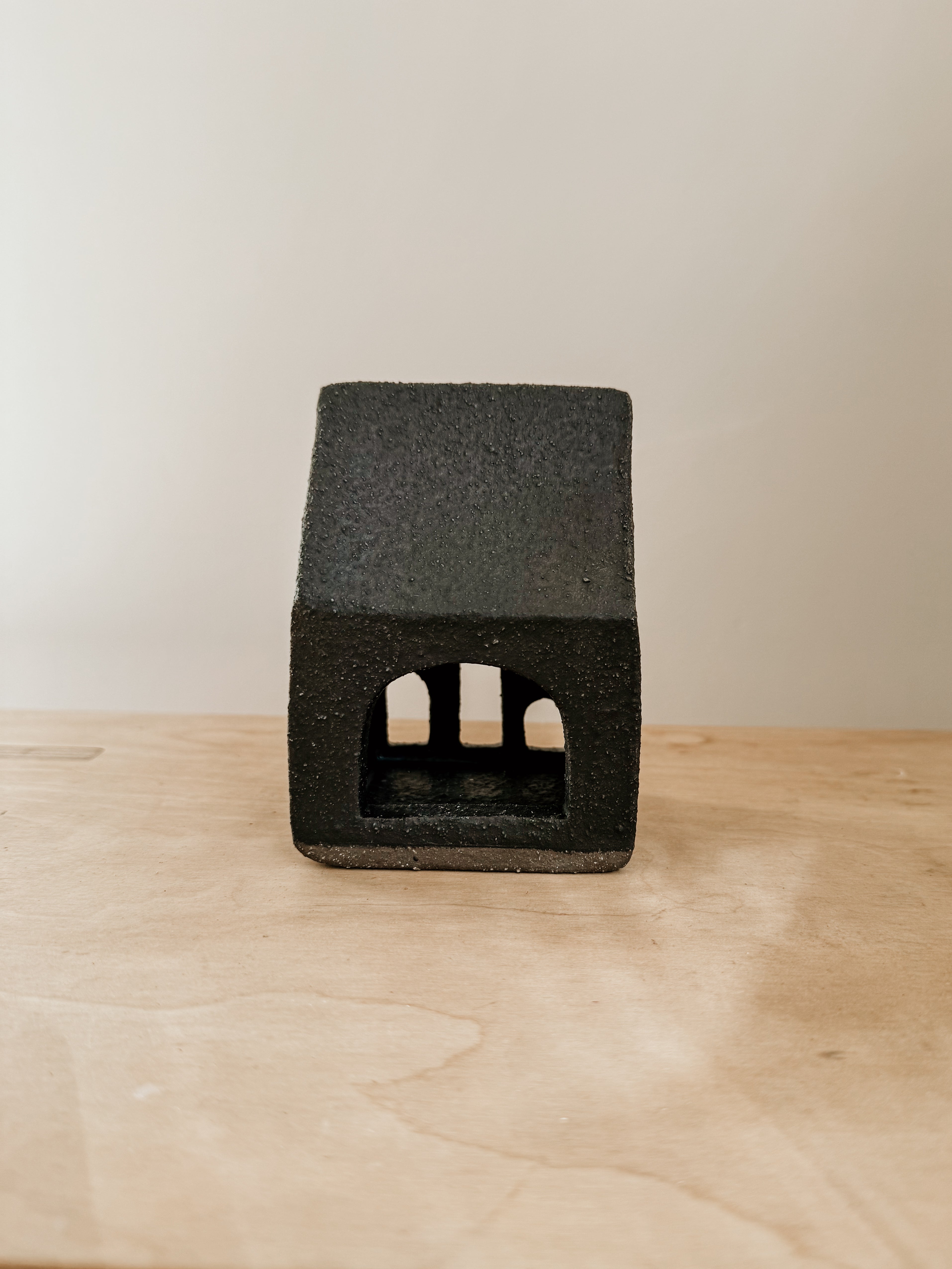 Small black tea light house candle holder by Delphine, made of ceramic, with a cozy house design for ambient lighting.