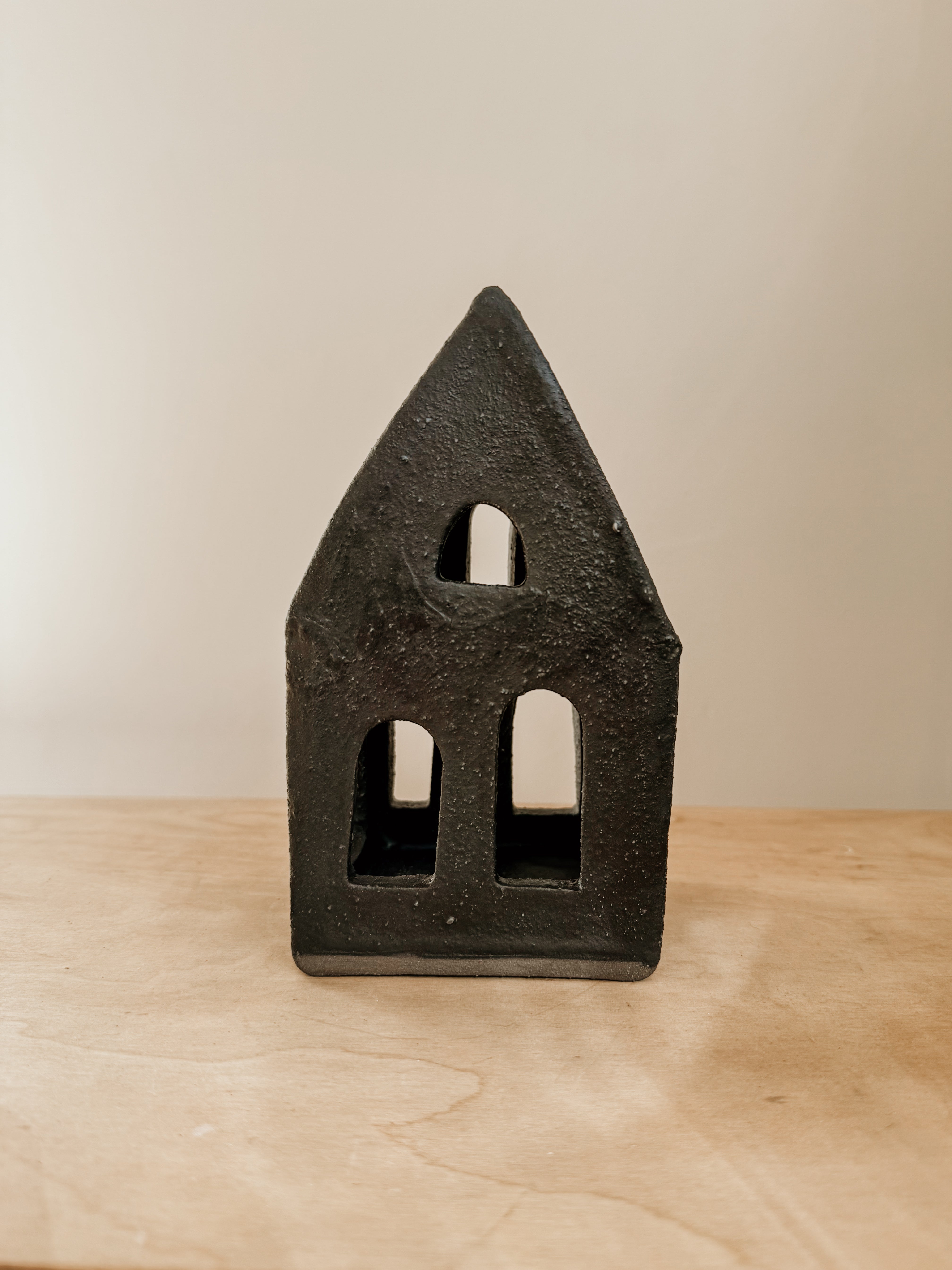 Large black Delphine Tea Light House candle holder on a neutral background, showcasing its detailed lighthouse design.