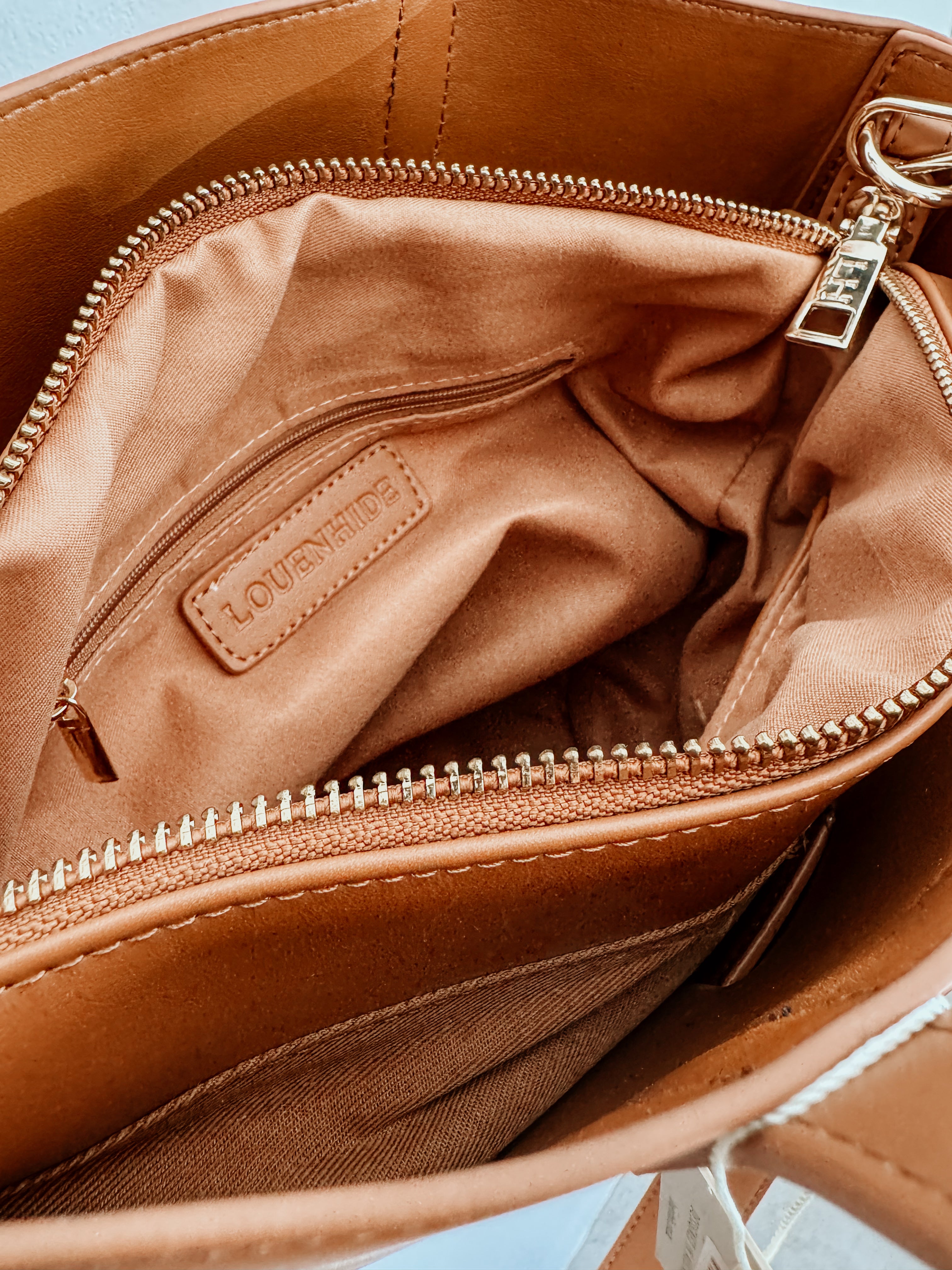 Tan LouenHide Bettina Bucket Bag with adjustable strap and stylish design, shown on a clean background.
