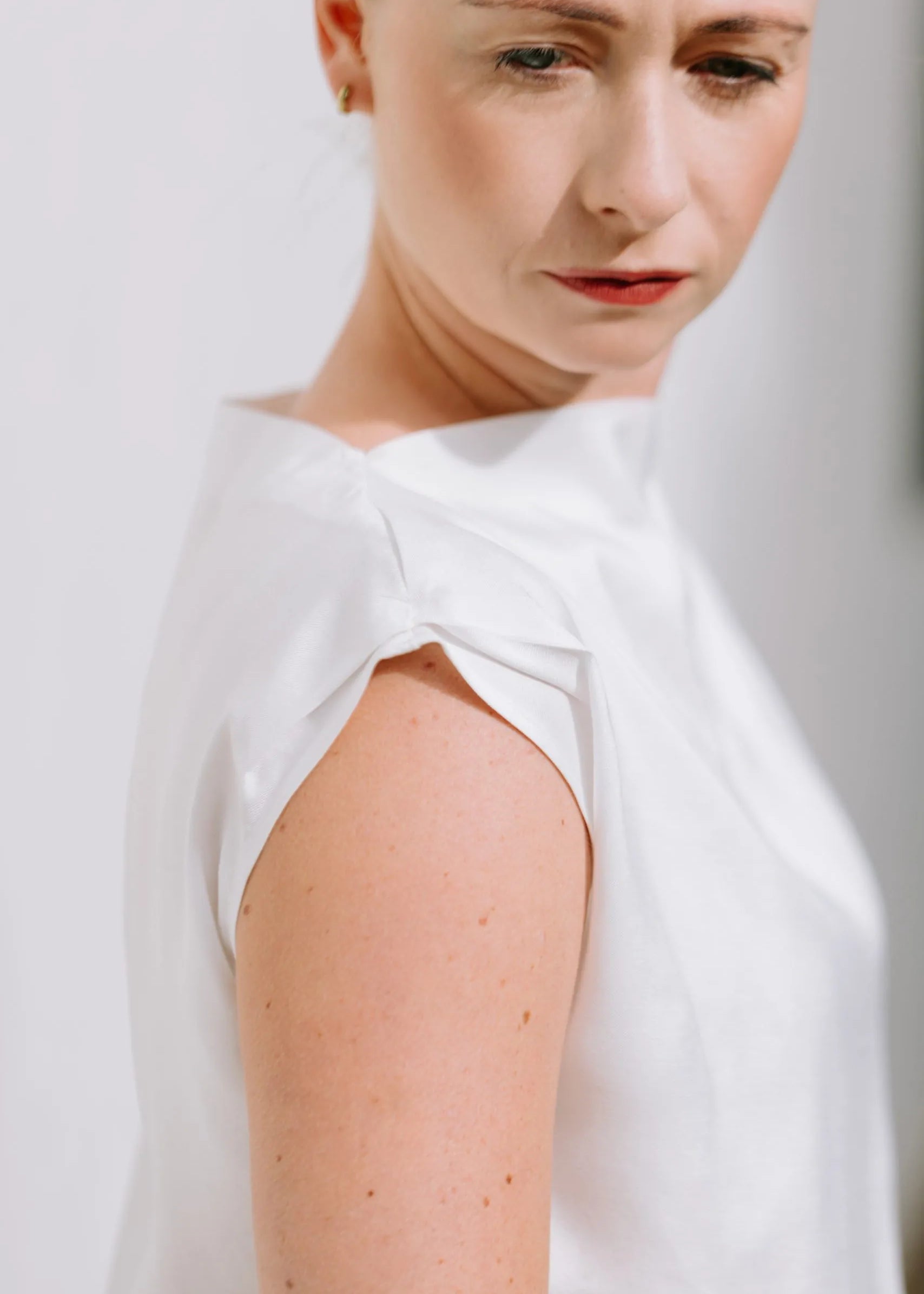 White Drape High Neck Top by Lika Designs, showcasing its flowing fabric and elegant high neckline on a consignment clothing hanger.