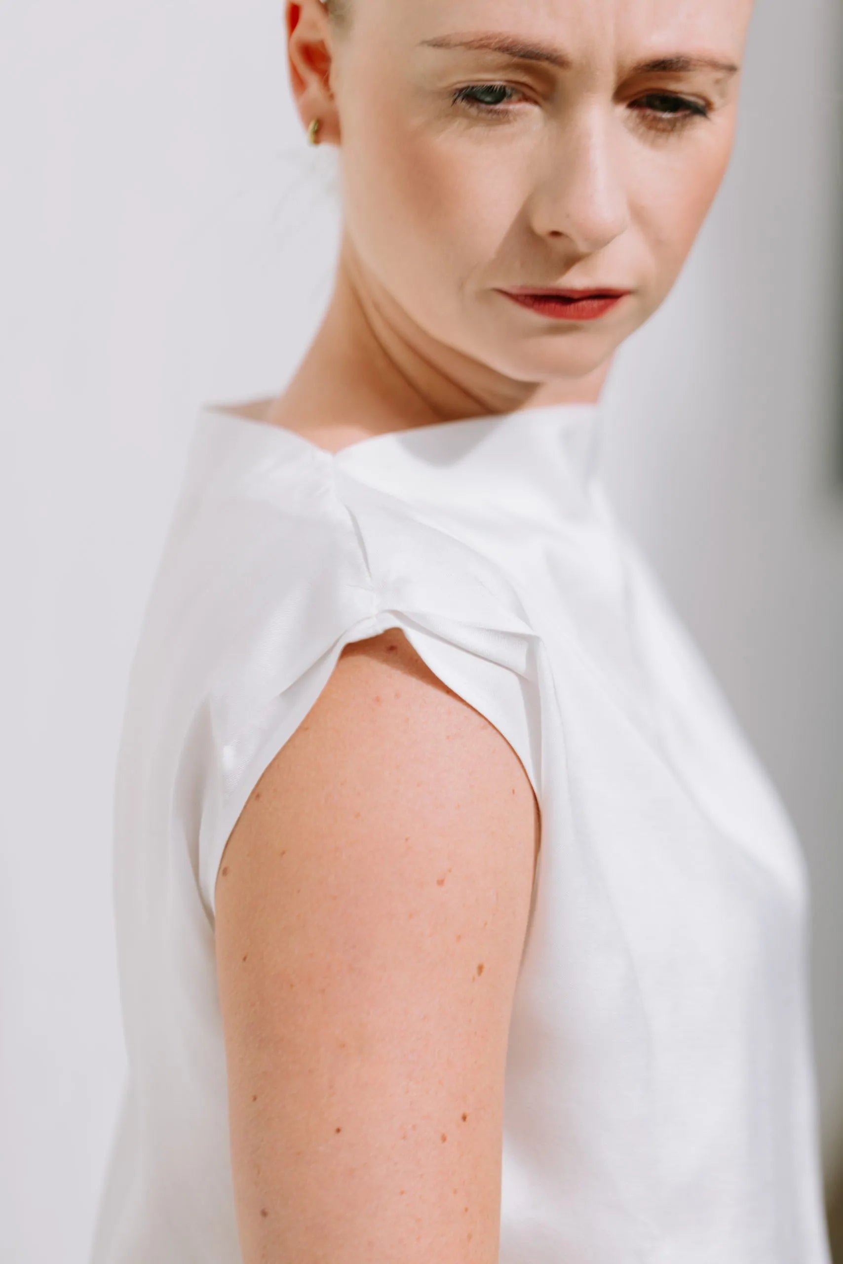 White Drape High Neck Top by Lika Designs, showcasing its flowing fabric and elegant high neckline on a consignment clothing hanger.