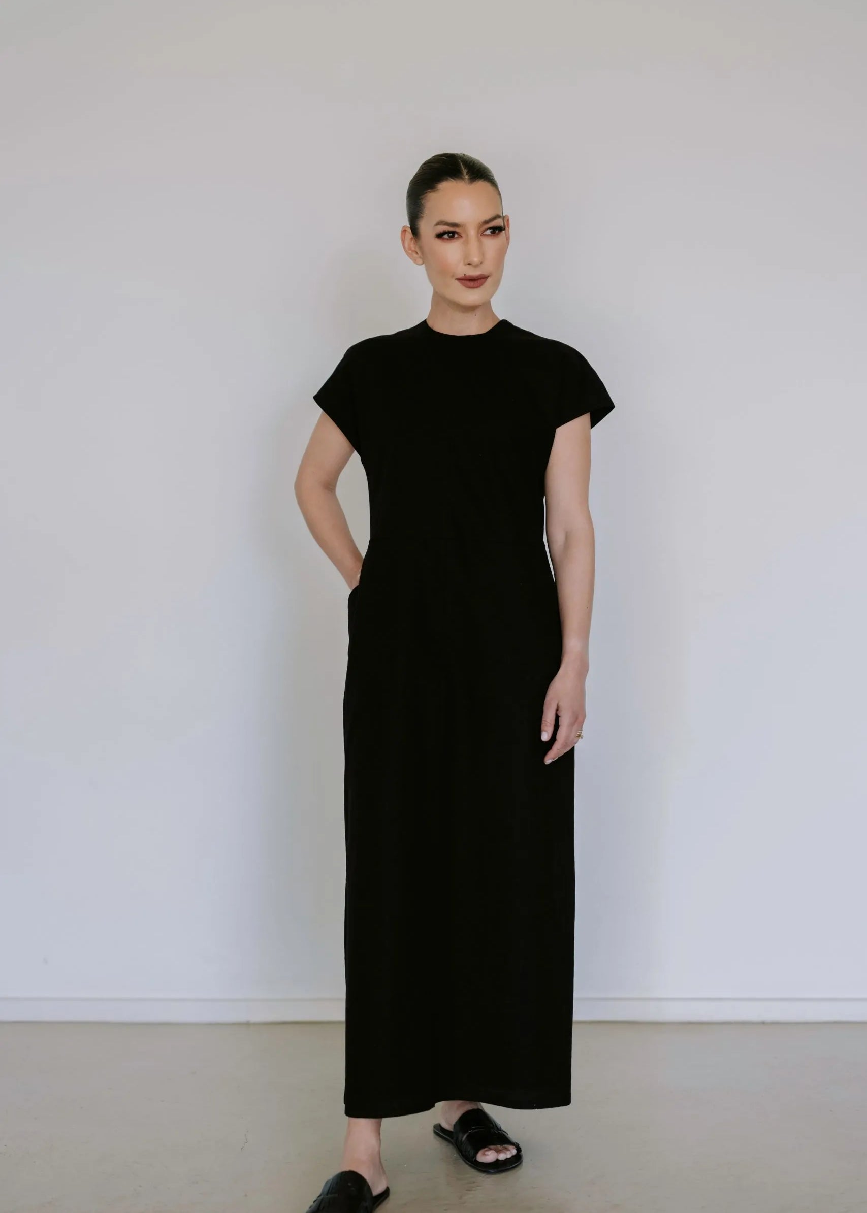 Black linen blend midi dress by Lika Designs, shown hanging on a clothing rack with a simple, elegant silhouette.