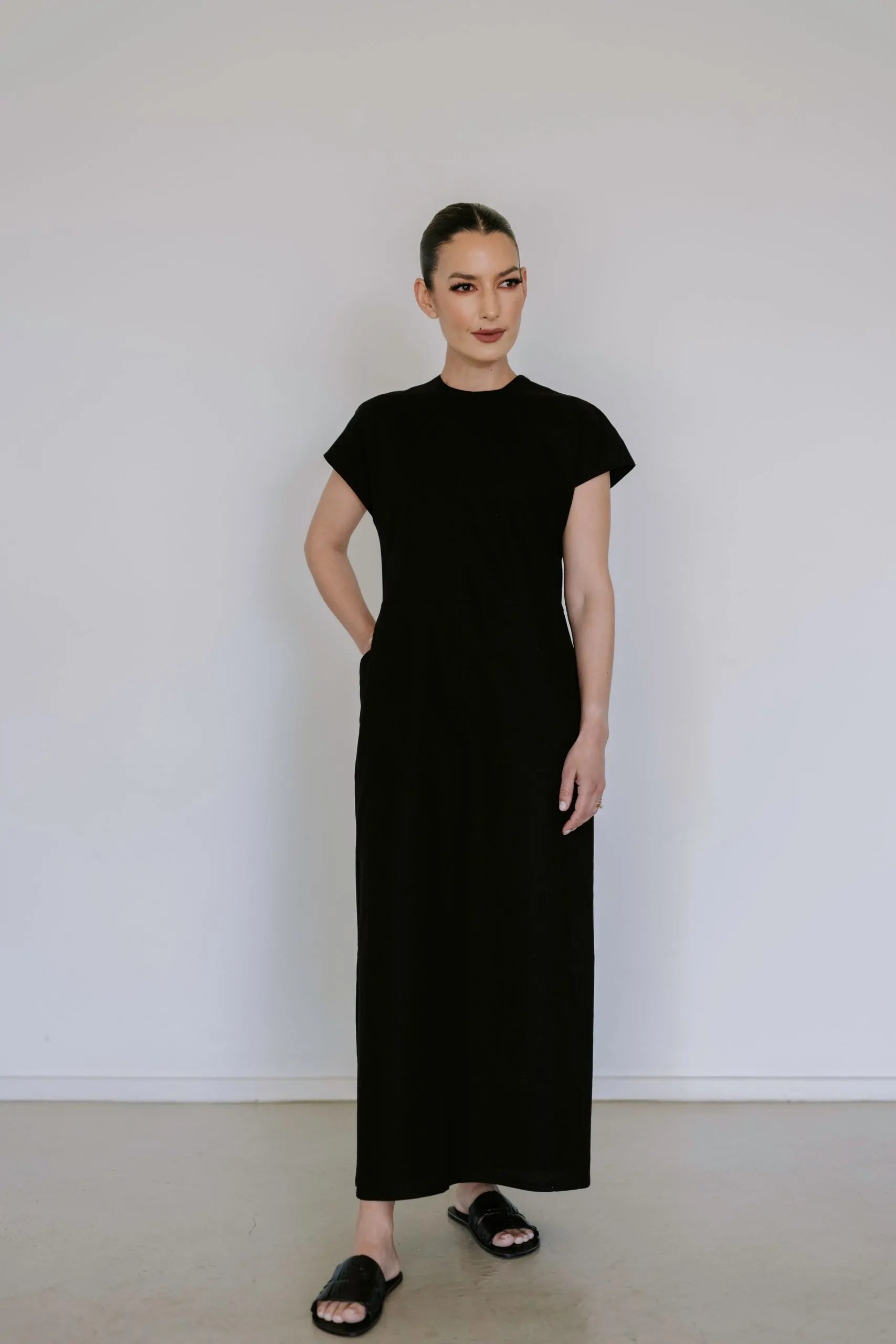 Black linen blend midi dress by Lika Designs, shown hanging on a clothing rack with a simple, elegant silhouette.