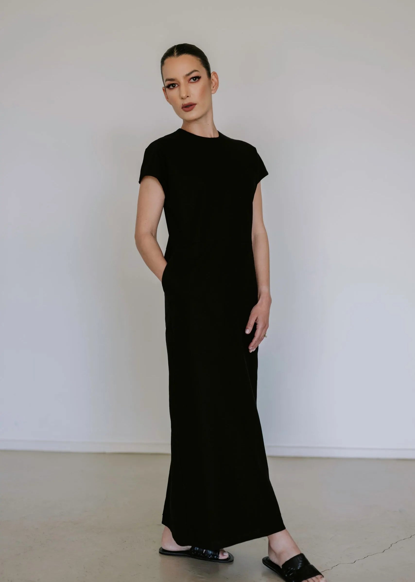Black linen blend midi dress by Lika Designs, shown on a hanger with a flowing, elegant silhouette and natural fabric texture.