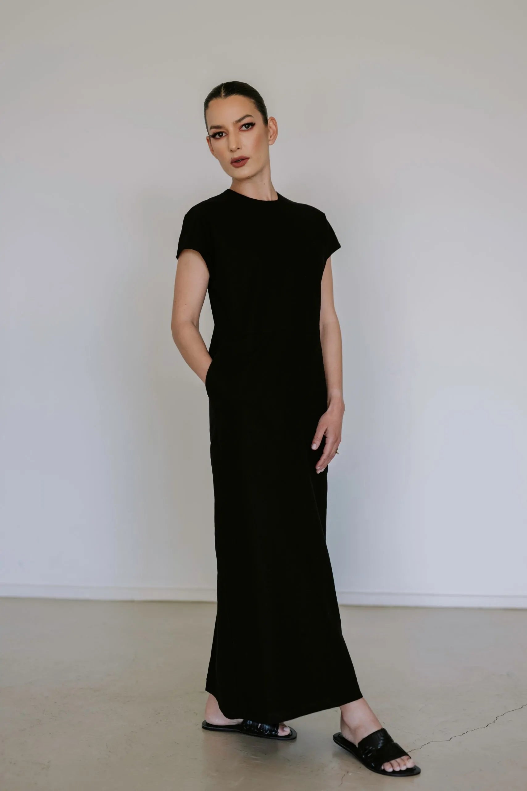 Black linen blend midi dress by Lika Designs, shown on a hanger with a flowing, elegant silhouette and natural fabric texture.