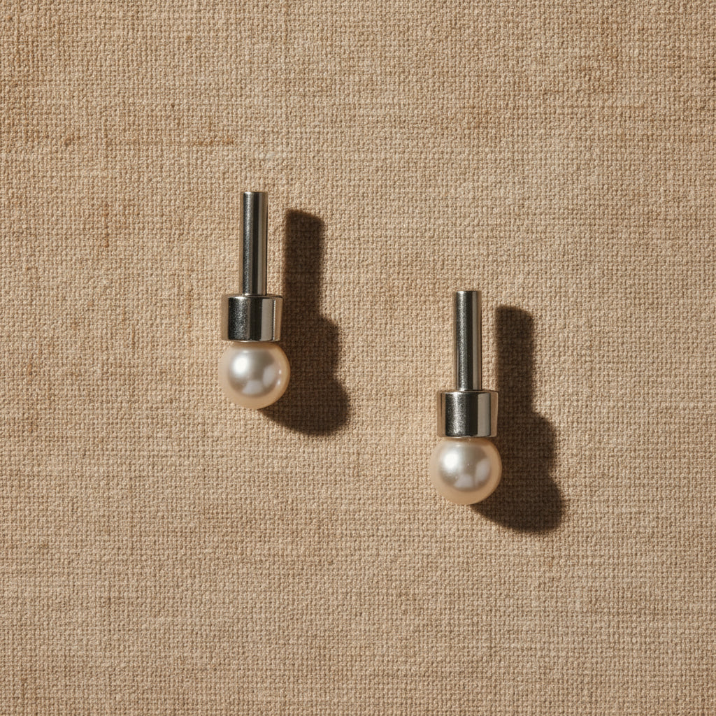 A pair of silver-colored earrings with a straight, round, metallic rod and an 8mm round white cultured pearl at the bottom.