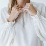 Trinity Denny reversible long sleeve shirt in milk color, made from natural fabric, displayed on a hanger.