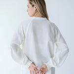 Trinity Denny reversible long sleeve shirt in white, made from natural fabric, displayed on a hanger with front and back views.