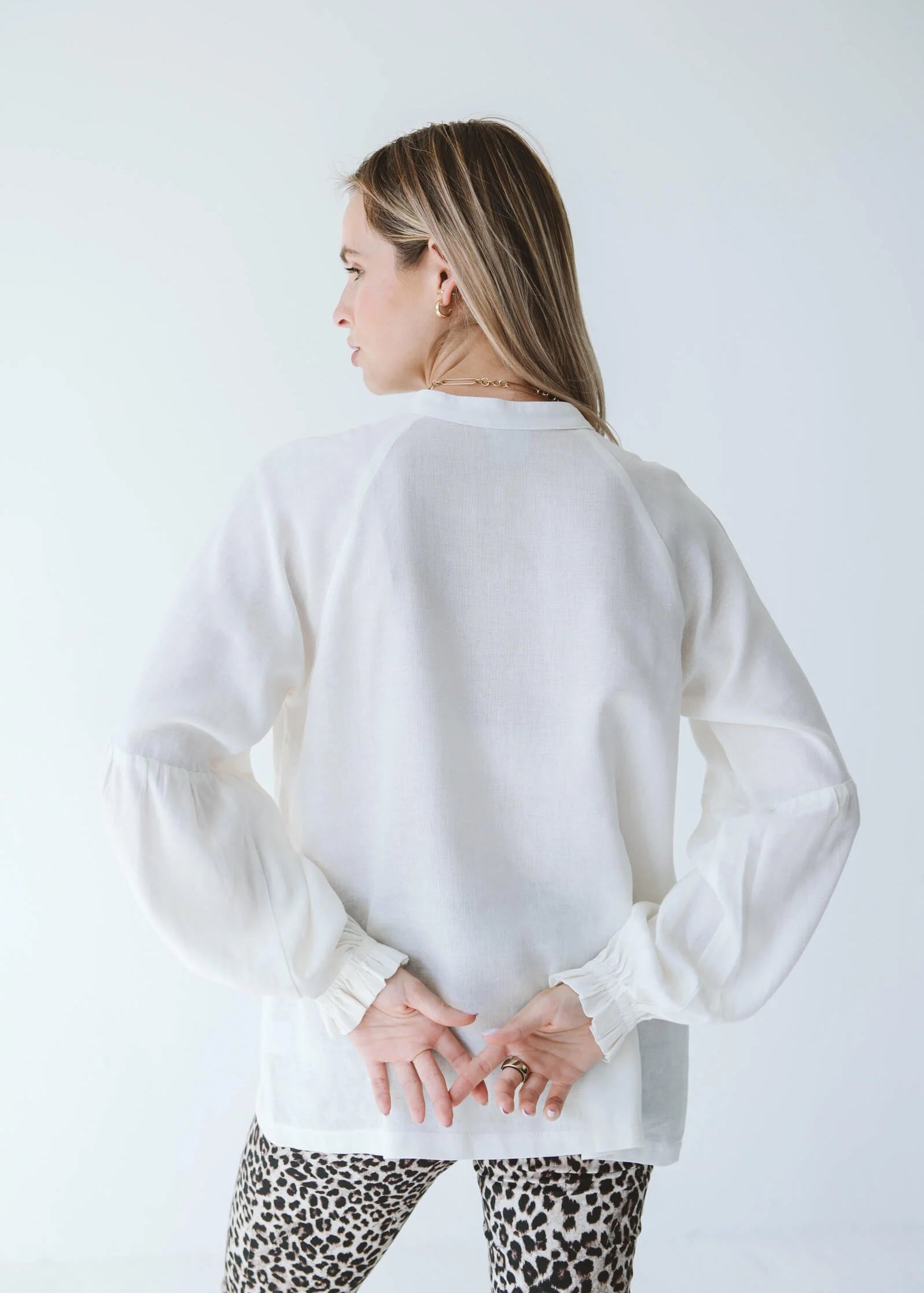 Trinity Denny reversible long sleeve shirt in white, made from natural fabric, displayed on a hanger with front and back views.