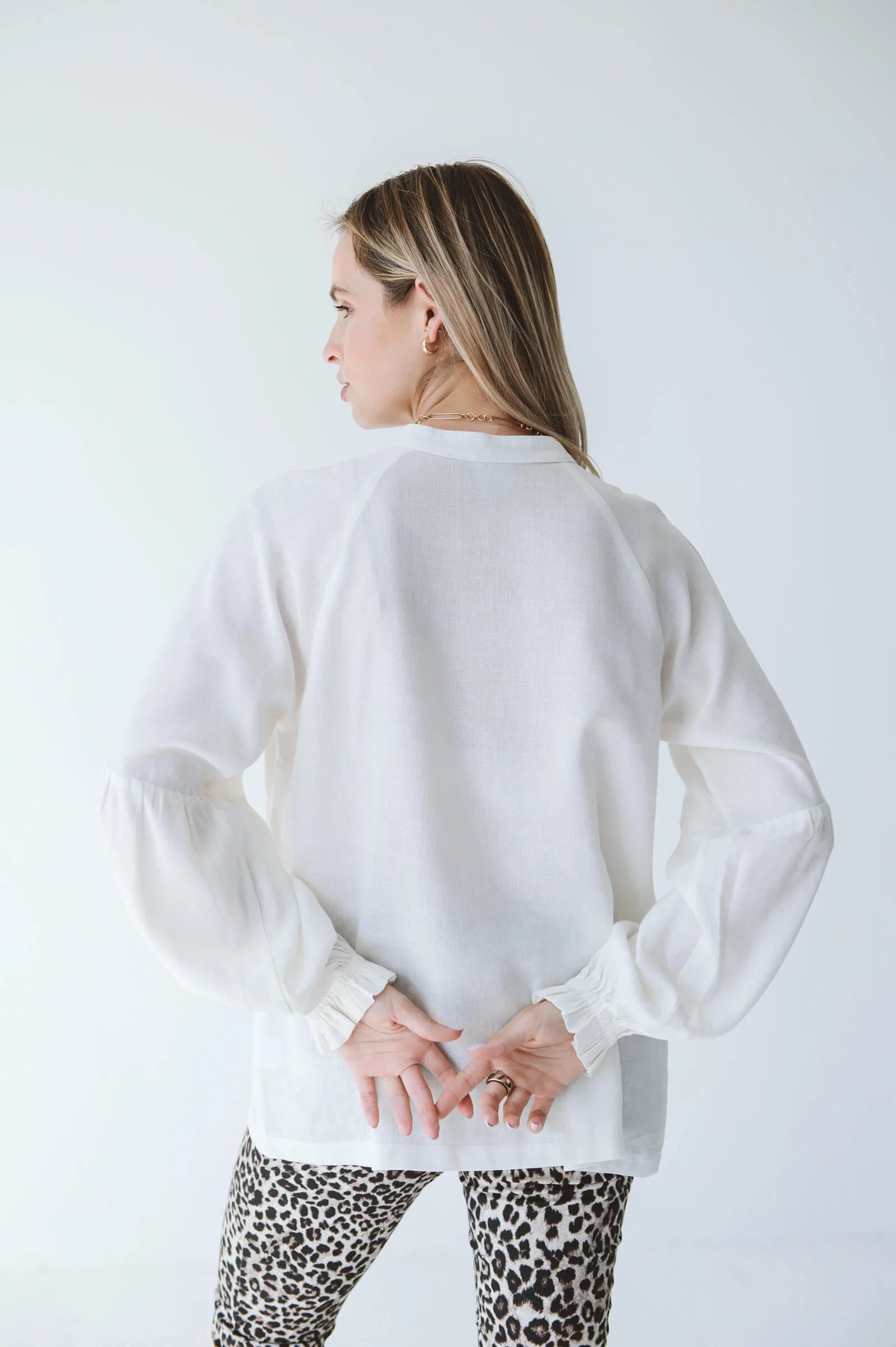 Trinity Denny reversible long sleeve shirt in white, made from natural fabric, displayed on a hanger with front and back views.
