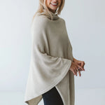 Cream Trinity poncho featuring a cozy, stylish design, perfect as warm outerwear for cold weather.